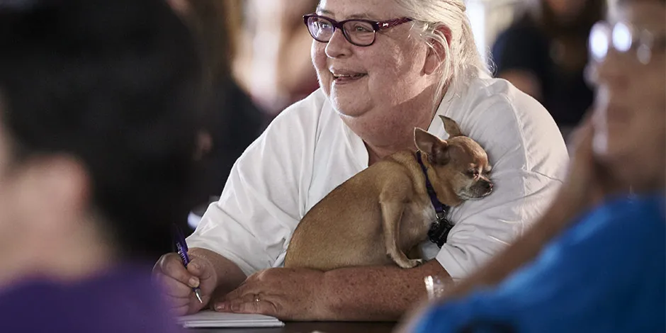 Chihuahua acompañando a su sonriente tutora. Son perros ideales para adultos mayores.