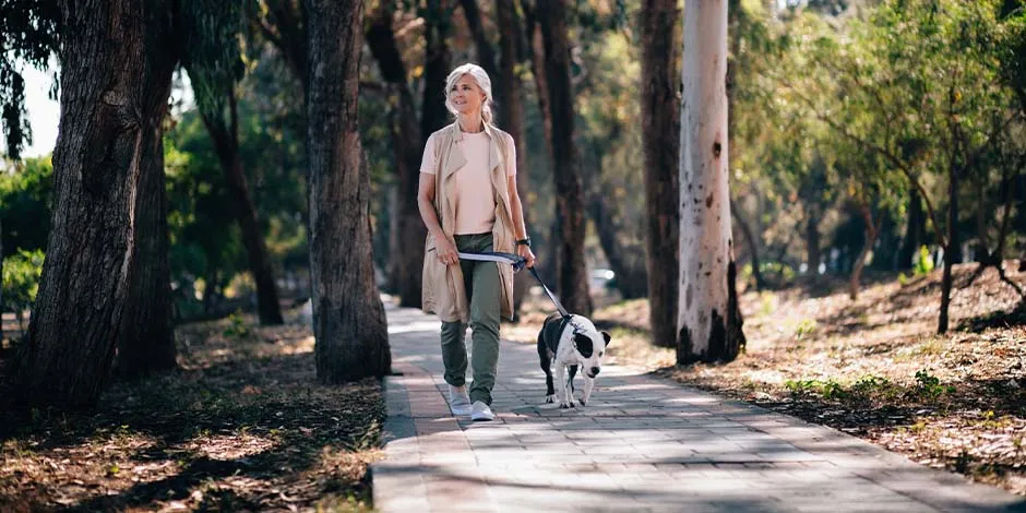 Tutora caminando junto a su mascota. Los perros para adultos mayores también requieren pasear.